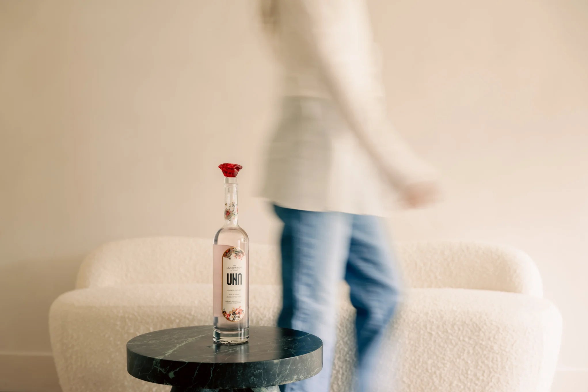 UNA Vodka bottle on a table with a person in the background.