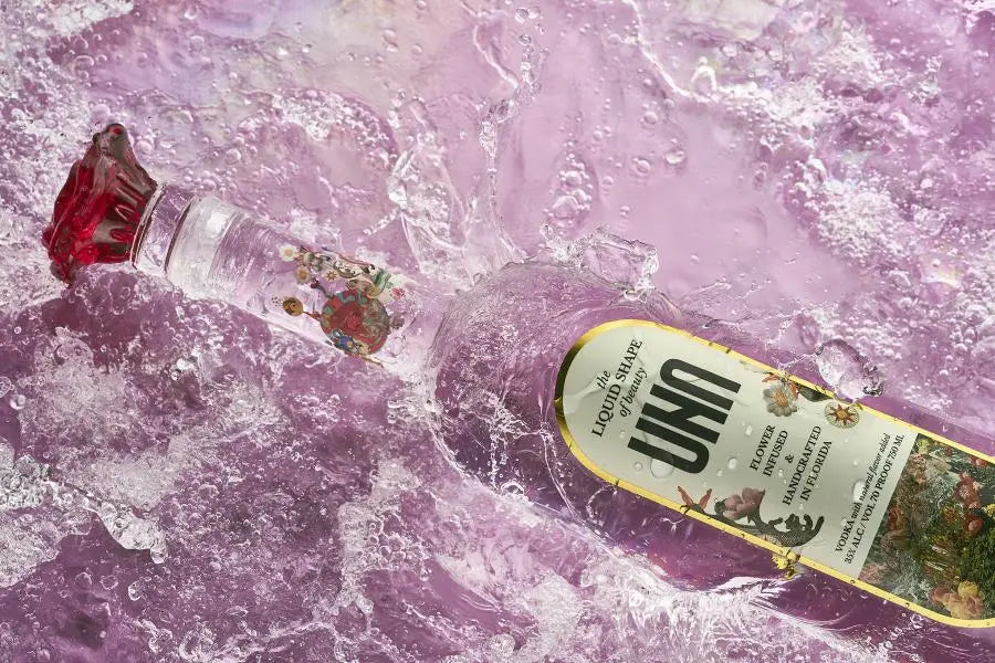UNA Vodka, flower-infused vodka bottle with liquid surrounding it
