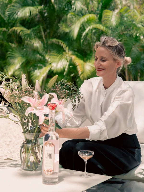 UNA Vodka founder & owner, Leti Fernández de Mesa, arranging flowers with UNA Vodka bottle on the table.